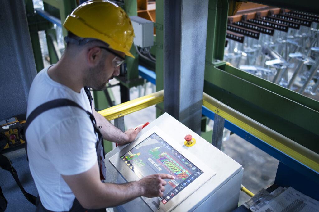 factory worker monitoring industrial machines production remotely control room